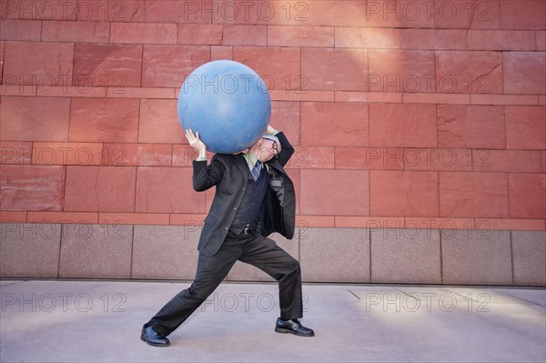 Caucasian businessman carrying heavy ball