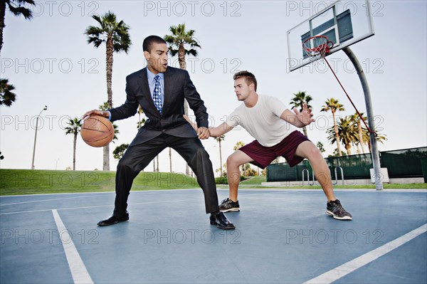 Businessman playing basketball with friend