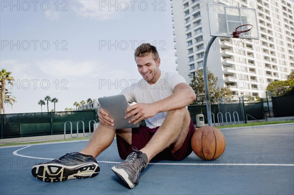 Caucasian man using digital tablet on basketball court