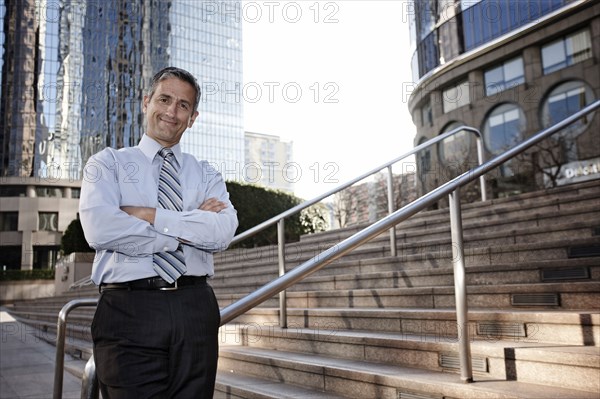 Hispanic businessman standing outdoors with arms crossed