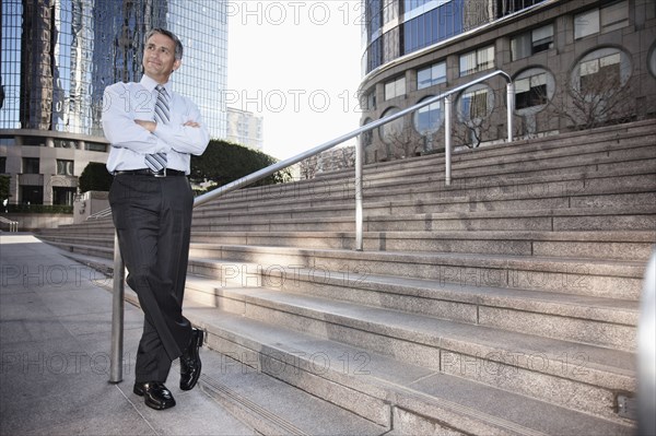 Hispanic businessman standing outdoors with arms crossed