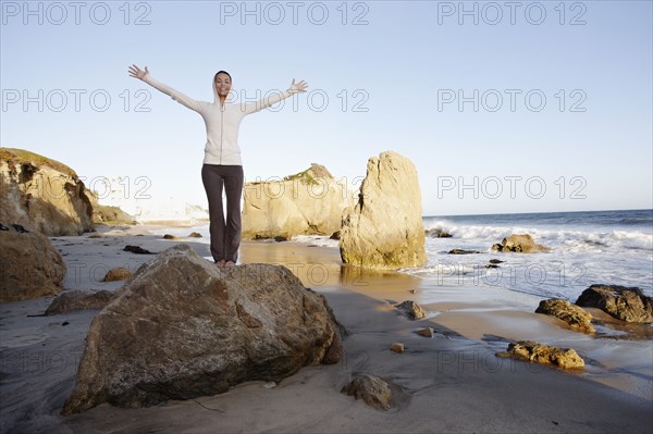 Hispanic woman on beach with arms outstretched