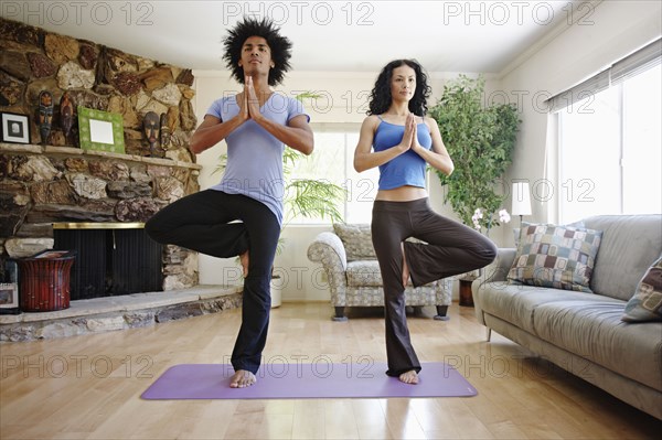 Couple practicing yoga in living room