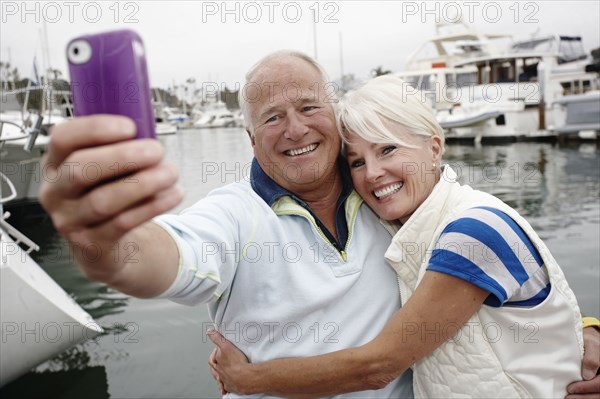 Smiling couple taking self-portrait at marina