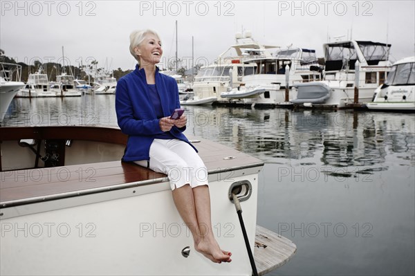 Woman sitting on boat text messaging on cell phone