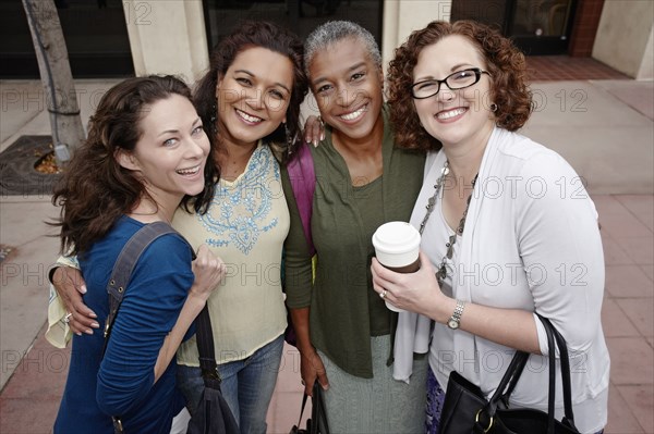 Smiling friends standing on sidewalk