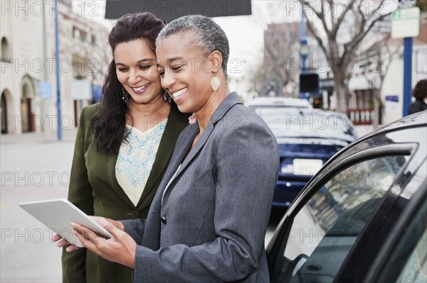 Businesswomen looking at digital tablet outdoors