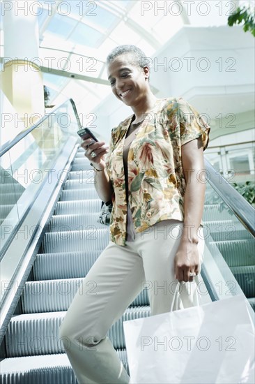 Black woman text messaging on escalator