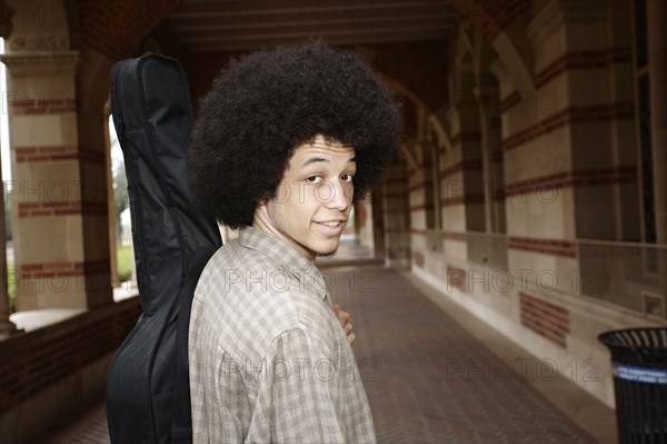 Man with afro carrying guitar in case