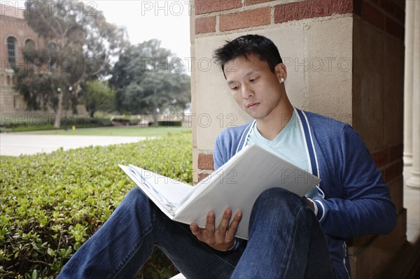 Mixed race student looking at notebook