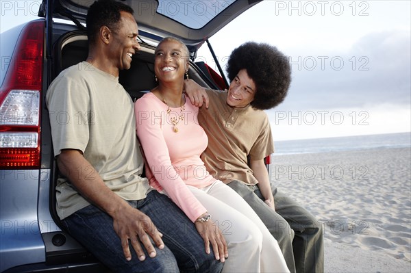 Family sitting on hatchback enjoying the beach