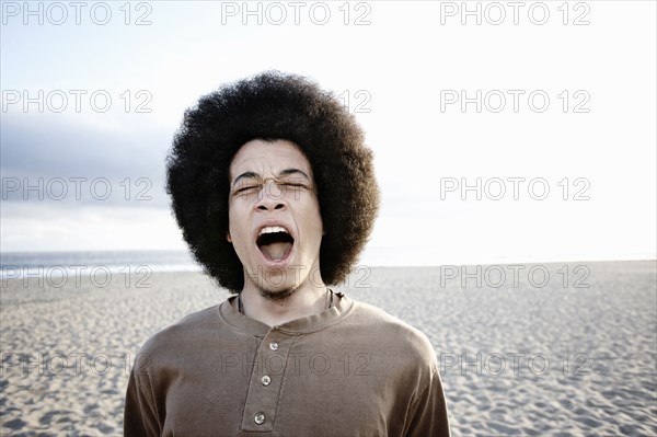 Mixed race man shouting on beach