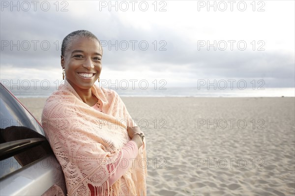 Black woman in shawl standing on beach