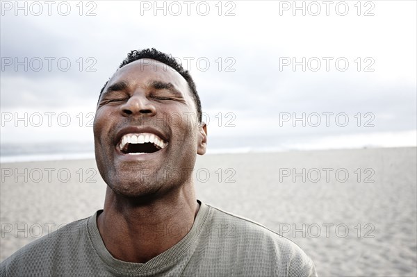 Black man laughing on beach