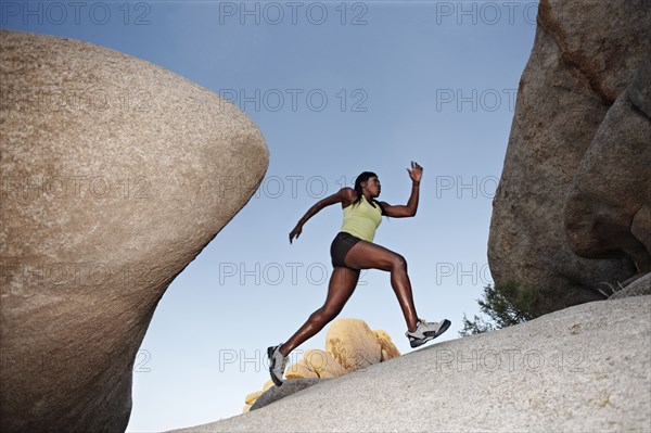 Woman running up boulder in remote area