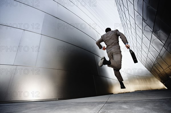 Businessman running down urban alley