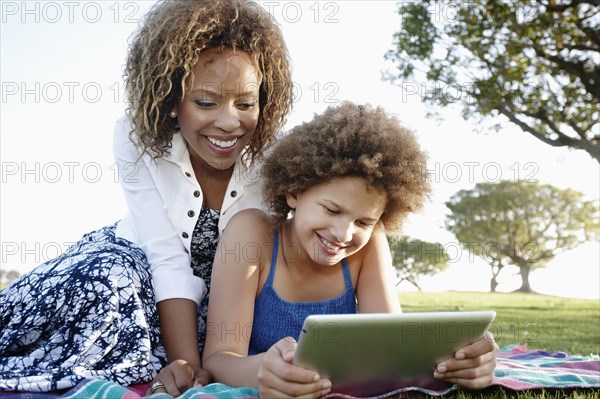 African American mother and daughter using digital tablet in park