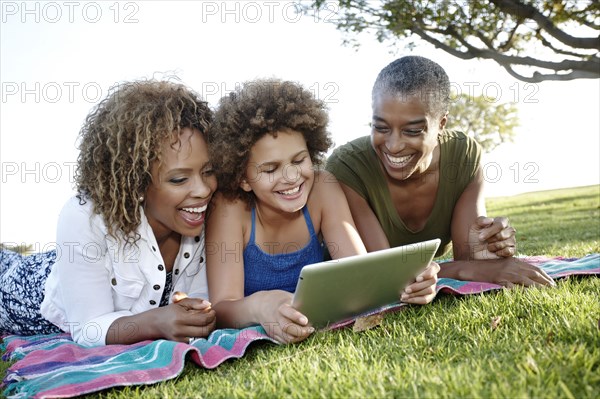 African American family using digital tablet in park