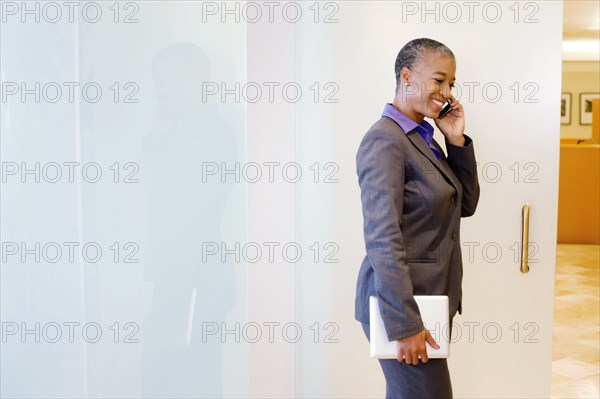 Black businesswoman holding digital tablet and using cell phone