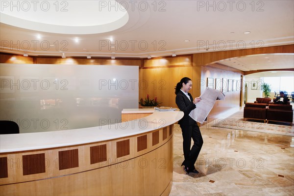 Mixed race businesswoman reading newspaper in office