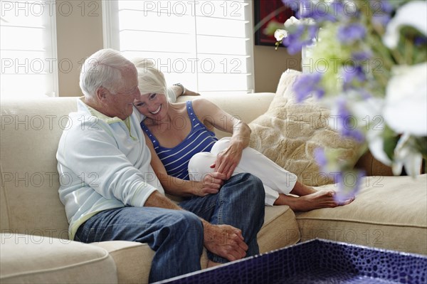 Caucasian couple hugging on sofa