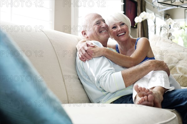 Caucasian couple hugging on sofa