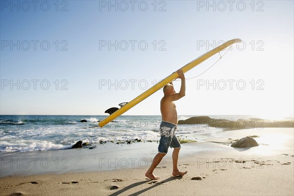 Caucasian man carrying paddleboard