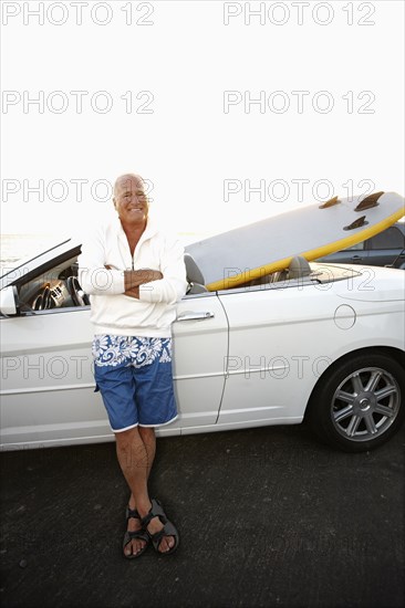 Caucasian man standing with car and paddleboard