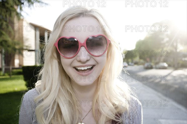 Smiling Caucasian woman in heart-shaped sunglasses