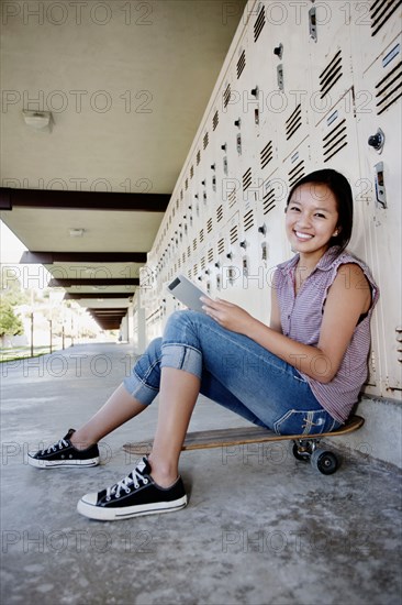 Chinese teenager on skateboard using digital tablet