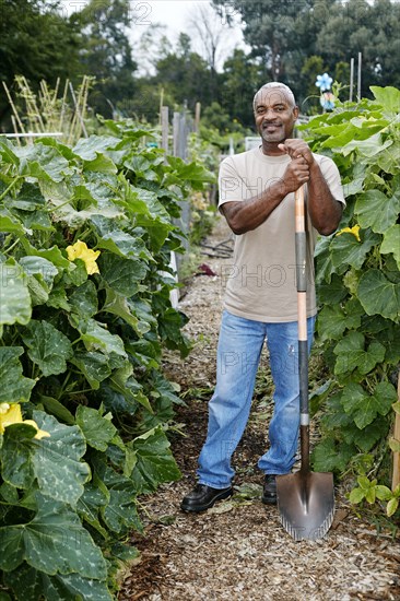 Black man leaning on shovel in community garden