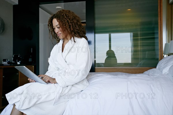 Mixed race woman using digital tablet in hotel room