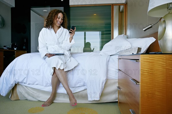 Mixed race woman text messaging in hotel room