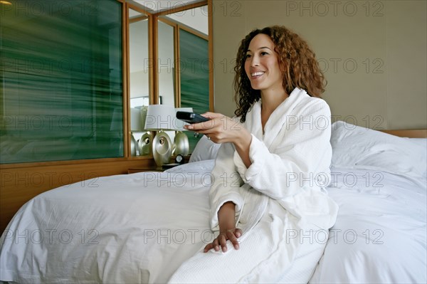 Mixed race woman watching television in hotel room