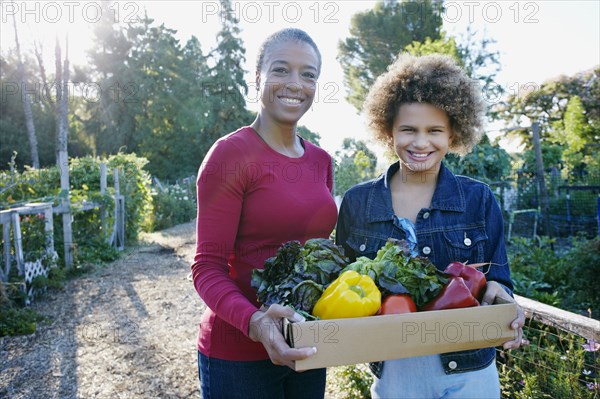 Mother and daughter gathering vegetables in community garden