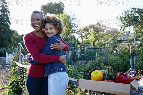 Mother and daughter gathering vegetables in community garden