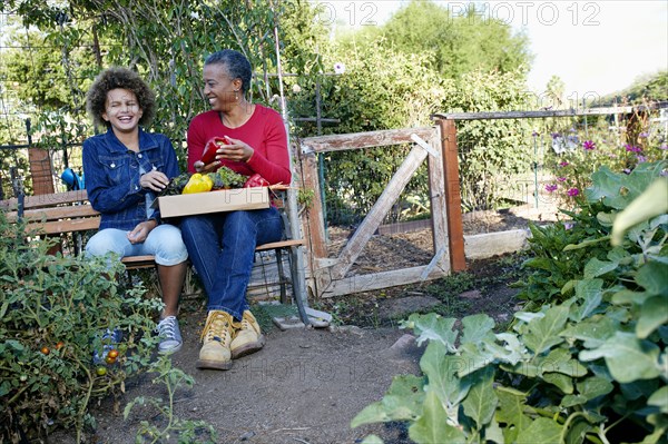 Mother and daughter gathering vegetables in community garden