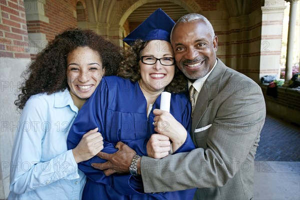 Proud family hugging graduate