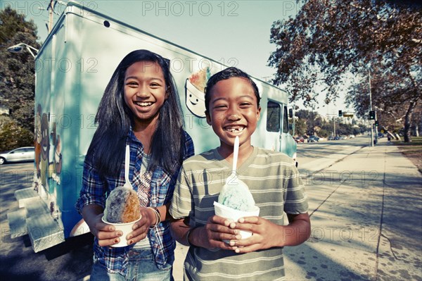 Mixed race children eating ice cream from truck