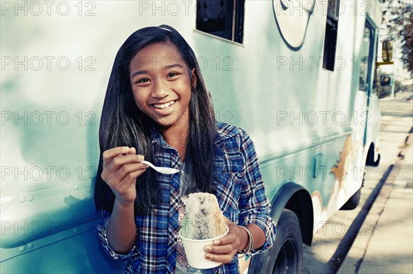 Mixed race girl eating ice cream from truck