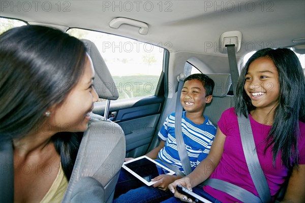 Mother watching children use technology in car