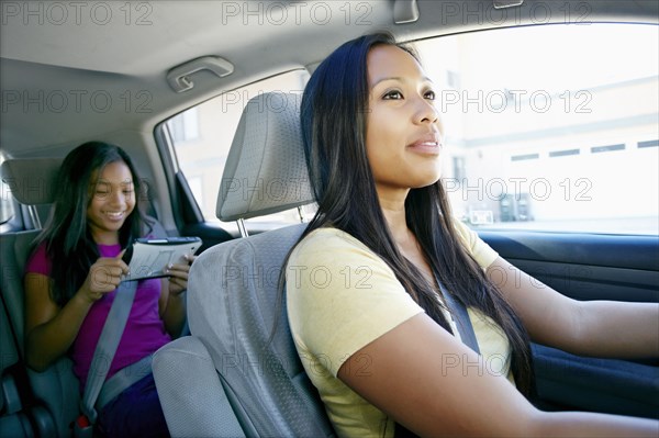 Mother watching daughter use technology in car