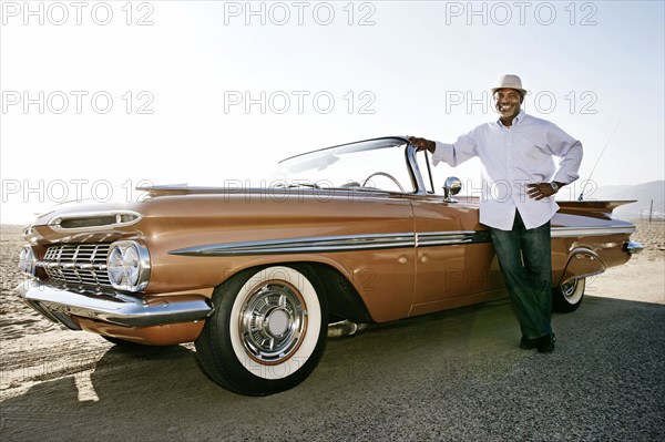 Black man leaning on convertible