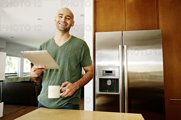 Hispanic man using tablet computer in kitchen