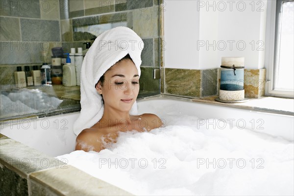 Mixed race woman having bubble bath