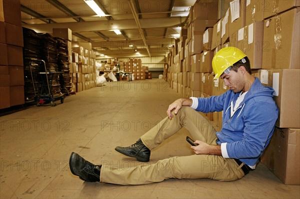 Caucasian worker using cell phone in warehouse