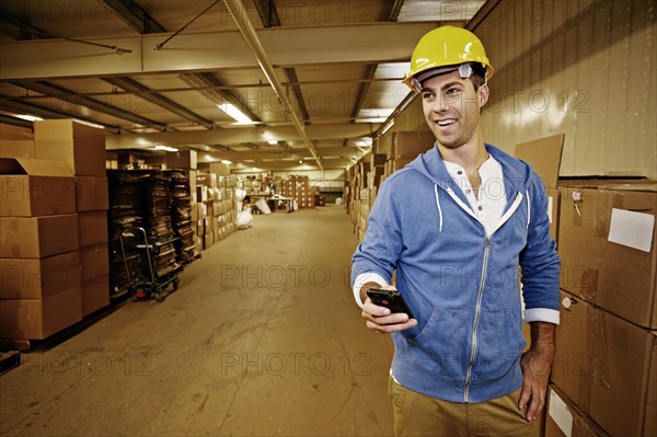 Caucasian worker using cell phone in warehouse