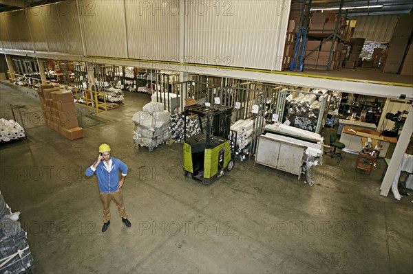 Caucasian worker talking on cell phone in warehouse