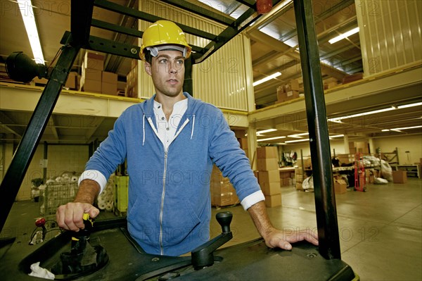 Caucasian worker driving machinery in warehouse