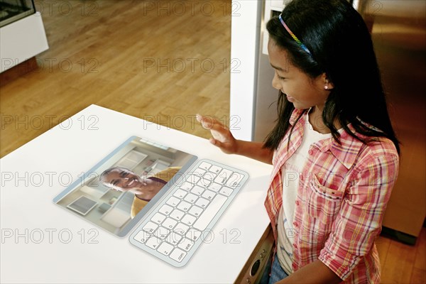 Girl waving at mother in computer in table